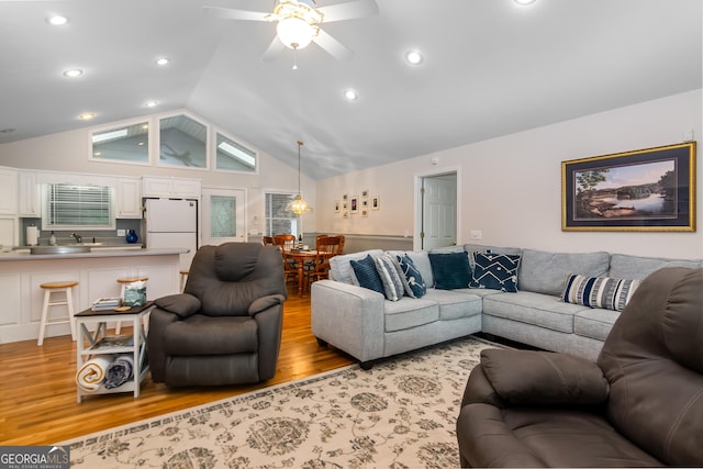 living room featuring ceiling fan, light hardwood / wood-style floors, sink, and high vaulted ceiling