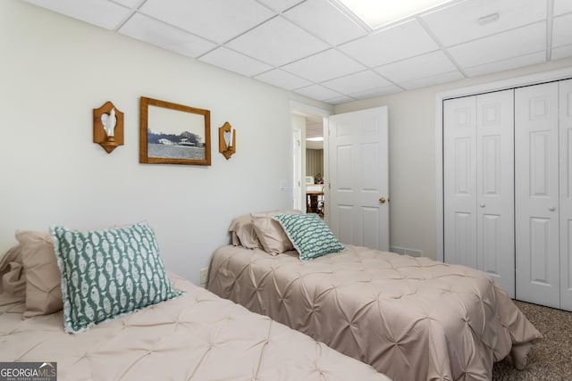 bedroom with a paneled ceiling, a closet, and carpet floors