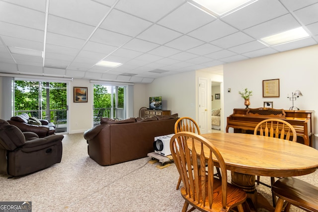 carpeted dining space featuring a paneled ceiling