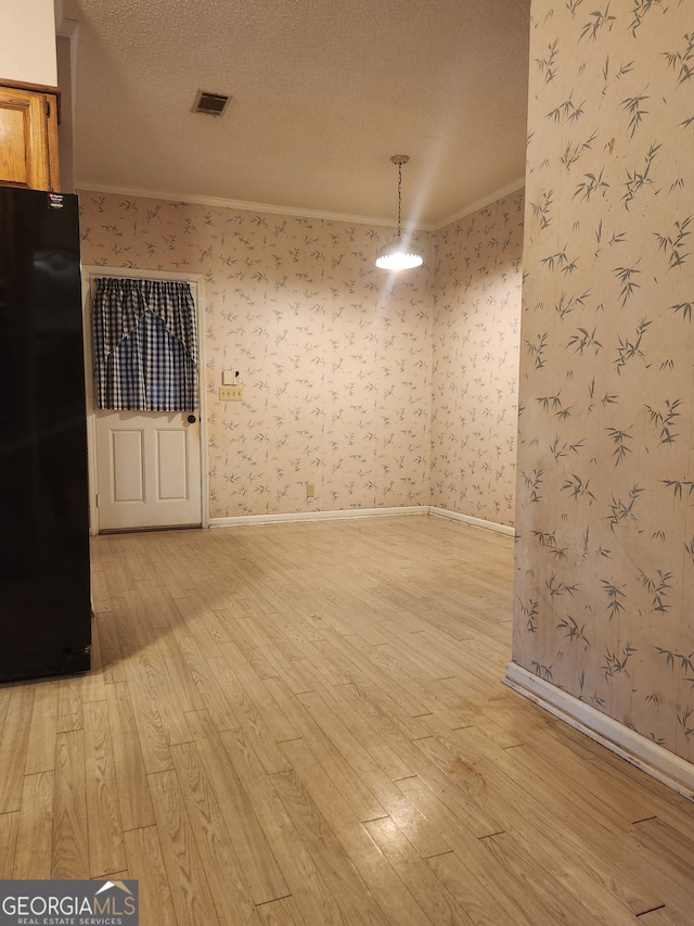 spare room featuring hardwood / wood-style flooring, a textured ceiling, and ornamental molding