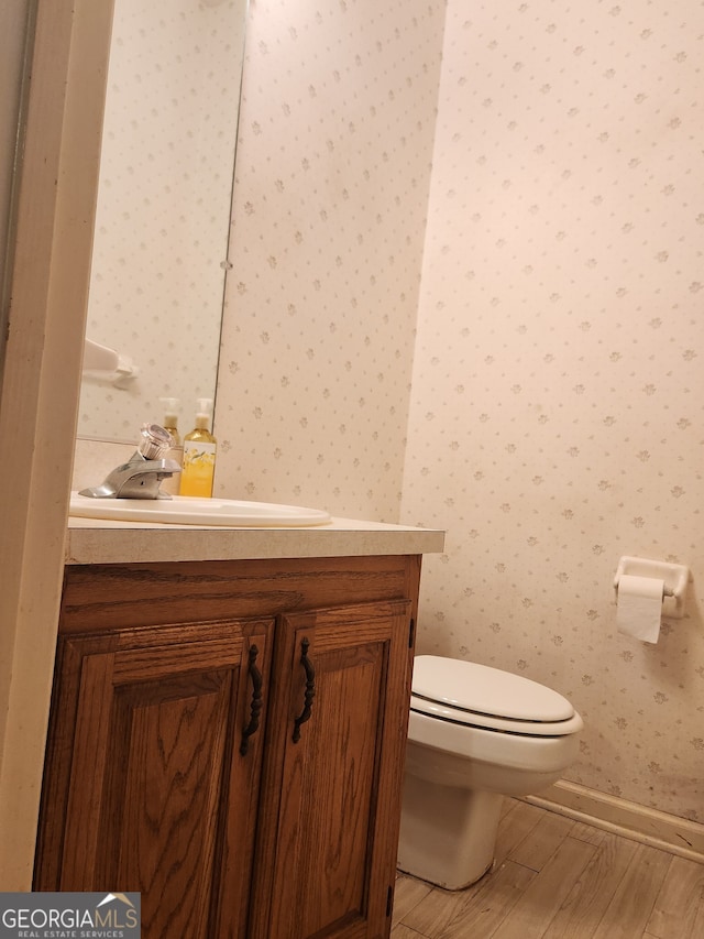 bathroom with toilet, vanity, and hardwood / wood-style flooring