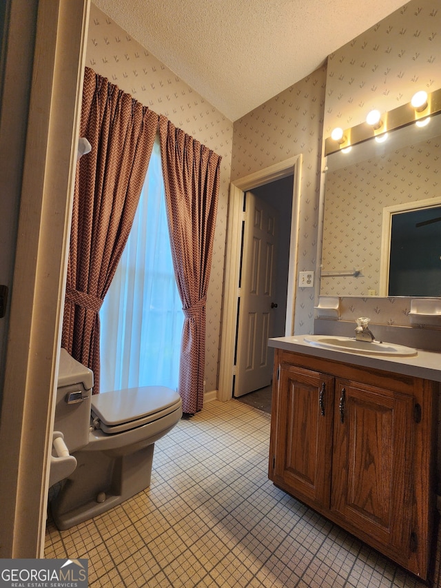 bathroom featuring a textured ceiling, vanity, tile patterned flooring, and toilet