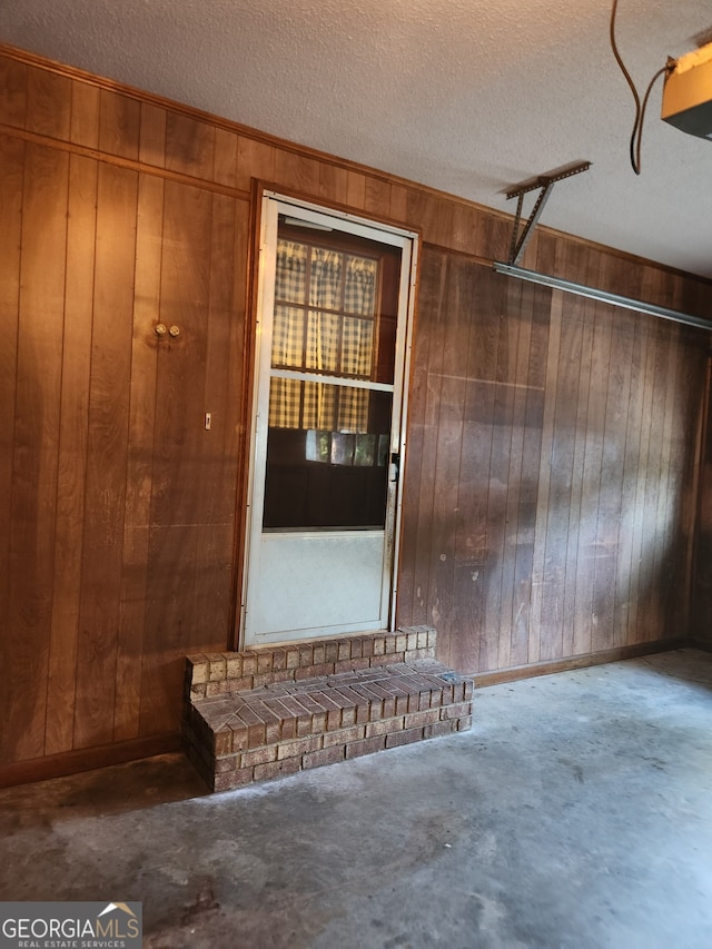 interior space with wood walls, concrete flooring, and a textured ceiling