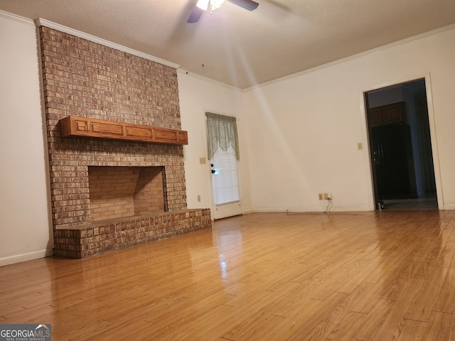 unfurnished living room with a fireplace, a textured ceiling, crown molding, light hardwood / wood-style floors, and ceiling fan