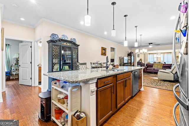 kitchen featuring sink, a center island with sink, decorative light fixtures, light stone countertops, and light hardwood / wood-style floors