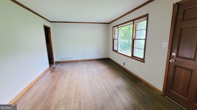 empty room featuring crown molding and hardwood / wood-style flooring