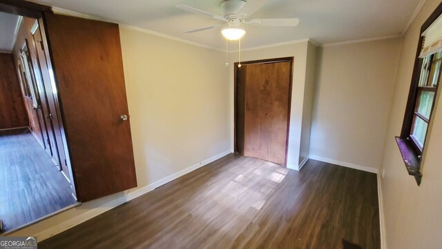 unfurnished bedroom with ceiling fan, dark hardwood / wood-style floors, crown molding, and a closet