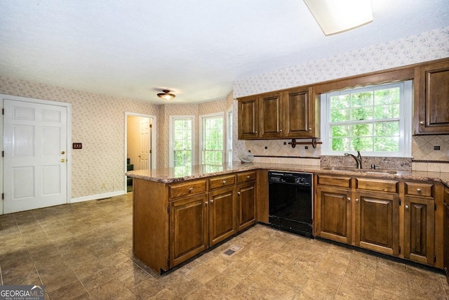 kitchen with black dishwasher, visible vents, a sink, a peninsula, and wallpapered walls