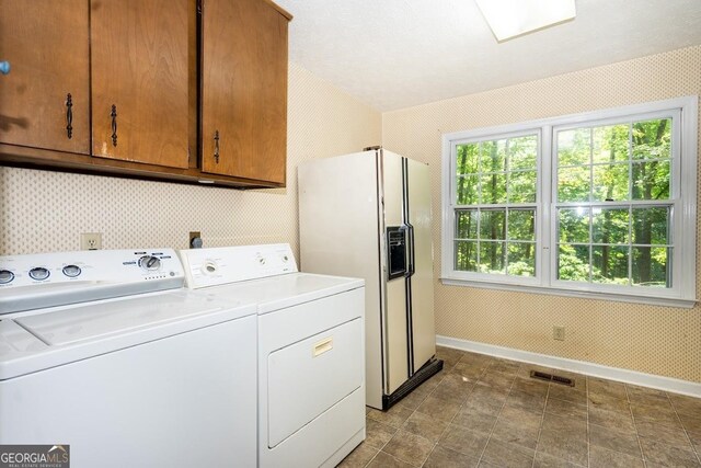 clothes washing area with washing machine and dryer, tile patterned floors, and cabinets