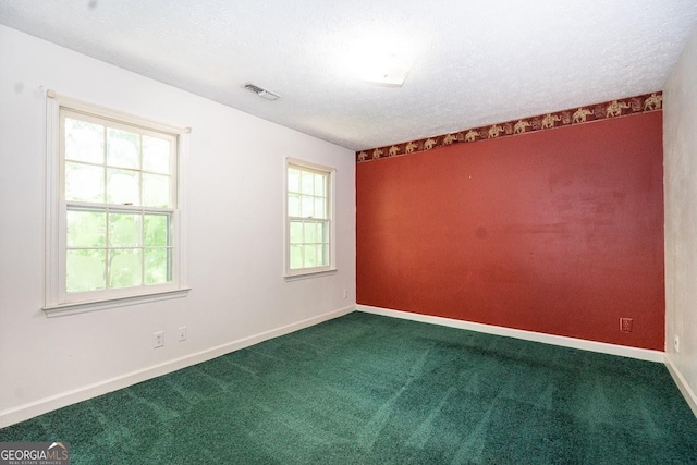 unfurnished room with baseboards, visible vents, dark colored carpet, and a textured ceiling