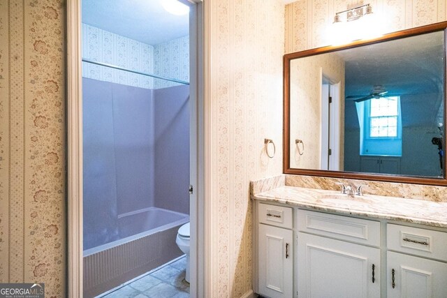 full bathroom featuring toilet, ceiling fan, tile patterned flooring,  shower combination, and vanity