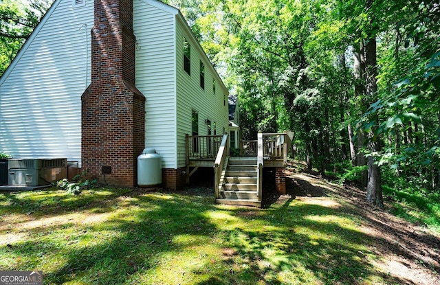 view of side of home featuring central AC unit, a lawn, a chimney, stairs, and a deck