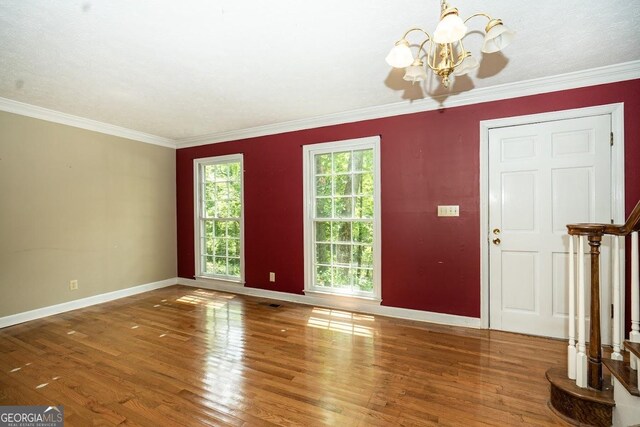 spare room featuring hardwood / wood-style floors, crown molding, and a notable chandelier