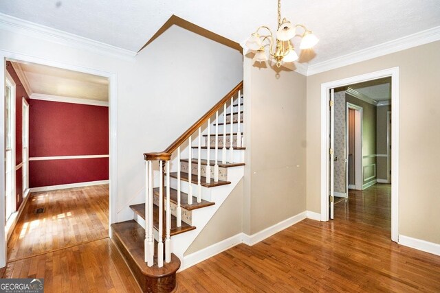 stairs featuring ornamental molding, hardwood / wood-style flooring, and a chandelier