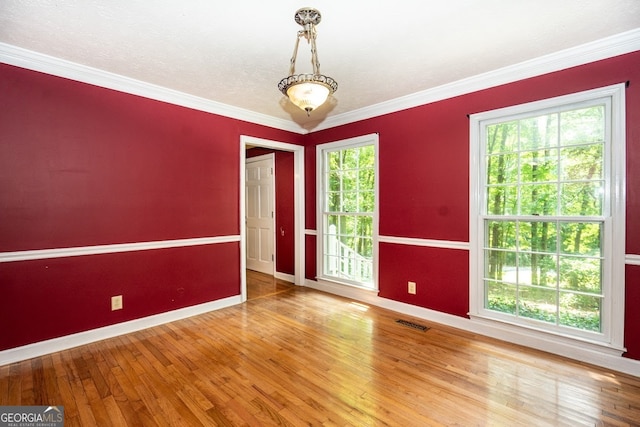 spare room featuring crown molding, hardwood / wood-style flooring, and plenty of natural light