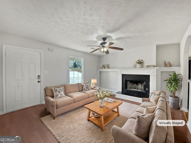 living room with ceiling fan, wood-type flooring, and a textured ceiling