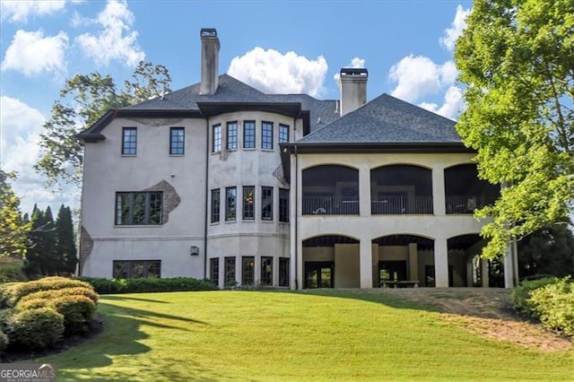 back of house featuring a lawn and a balcony