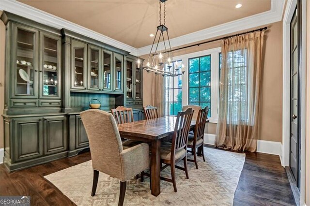 dining area with dark wood-type flooring, a chandelier, and crown molding