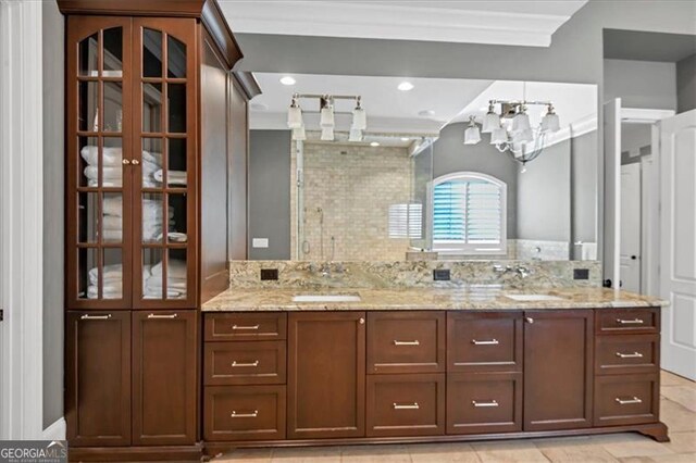 bathroom featuring an inviting chandelier, ornamental molding, tasteful backsplash, tile patterned flooring, and double sink vanity