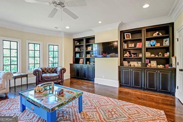 living area featuring ceiling fan, ornamental molding, dark hardwood / wood-style flooring, and built in shelves