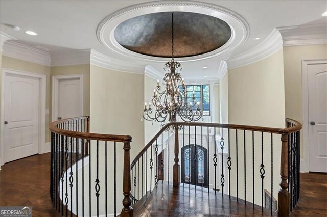 interior space with an inviting chandelier, ornamental molding, dark hardwood / wood-style flooring, and a tray ceiling