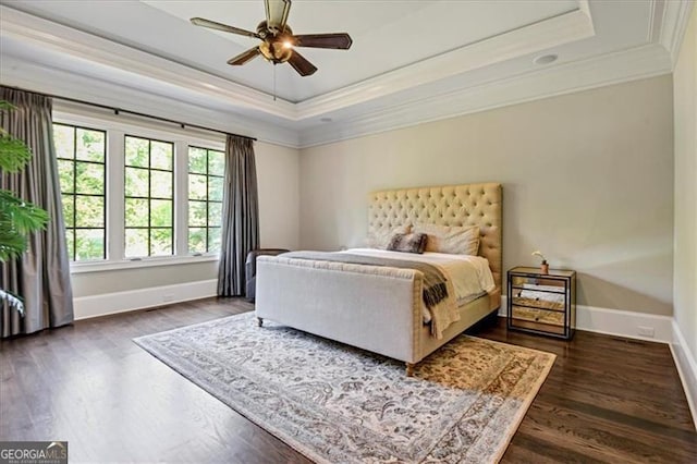 bedroom featuring ceiling fan, a raised ceiling, dark hardwood / wood-style flooring, and crown molding