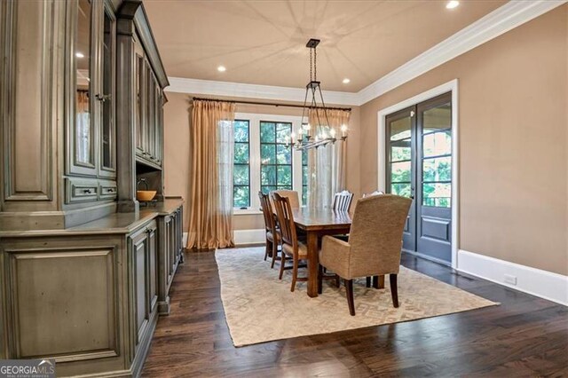 dining area featuring crown molding, dark hardwood / wood-style floors, a healthy amount of sunlight, and a chandelier