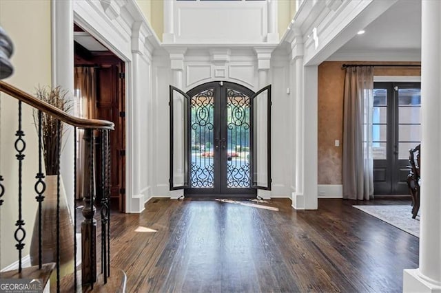 entryway with ornate columns, hardwood / wood-style floors, ornamental molding, and french doors