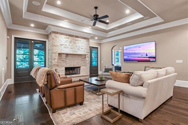 living room featuring a fireplace, a tray ceiling, and dark wood-type flooring