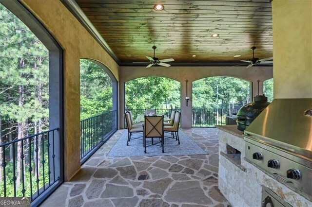 unfurnished sunroom with ceiling fan, a wealth of natural light, and wood ceiling