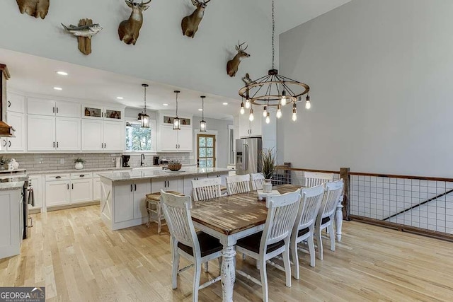 dining area with light wood-type flooring, an inviting chandelier, and sink