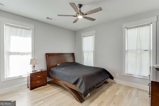 bedroom featuring ceiling fan, light hardwood / wood-style flooring, and multiple windows