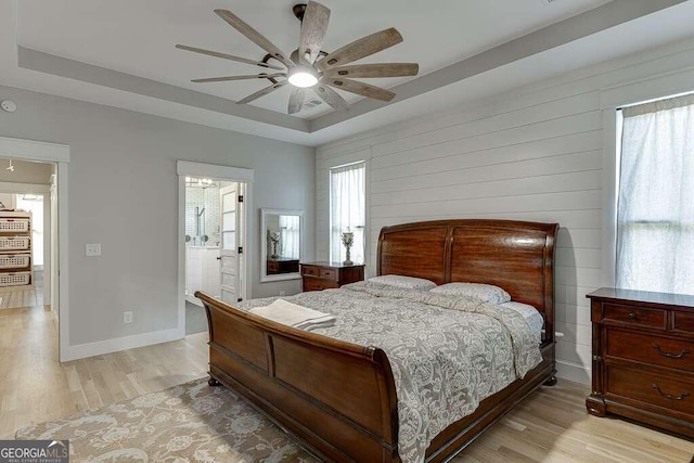 bedroom featuring multiple windows, connected bathroom, light hardwood / wood-style floors, and ceiling fan