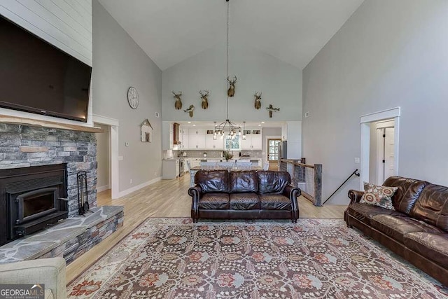 living room with light wood-type flooring, a stone fireplace, and high vaulted ceiling