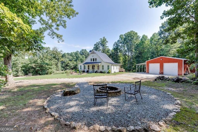 view of yard featuring an outdoor structure, a garage, and an outdoor fire pit