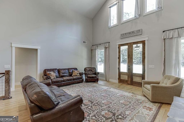 living room with wood-type flooring, french doors, and high vaulted ceiling