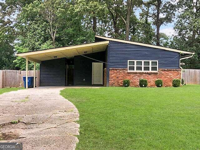 single story home featuring a front lawn and a carport