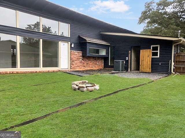 back of house featuring a lawn and central air condition unit