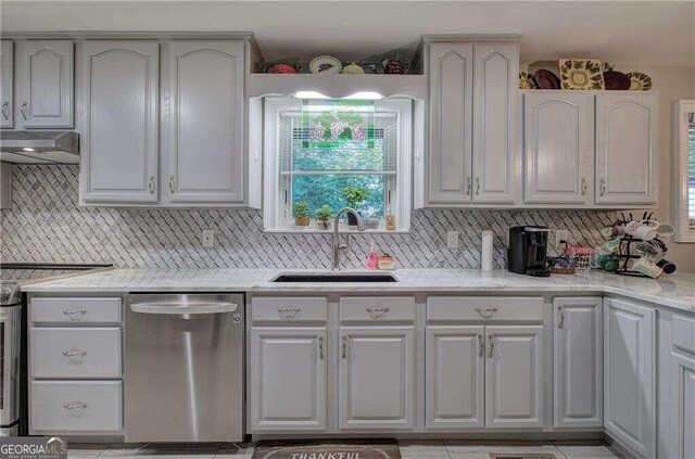 kitchen featuring dishwasher, sink, wall chimney exhaust hood, and a healthy amount of sunlight