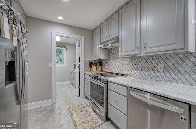 kitchen featuring appliances with stainless steel finishes, light stone countertops, light tile patterned flooring, gray cabinetry, and tasteful backsplash