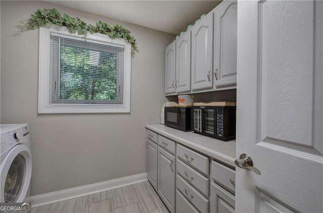 clothes washing area with washer / clothes dryer, light tile patterned flooring, and cabinets