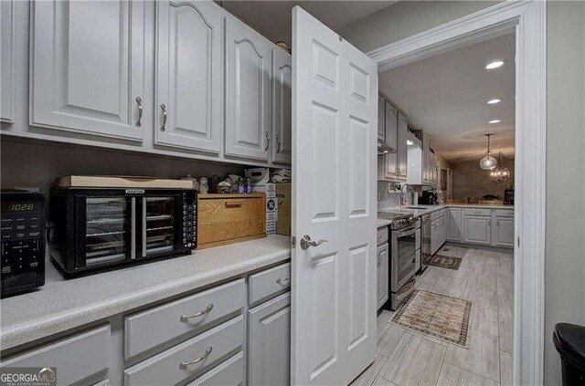 kitchen with gray cabinetry, light hardwood / wood-style flooring, stainless steel electric range oven, and sink