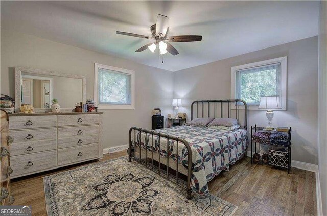 bedroom with ceiling fan, wood-type flooring, and multiple windows