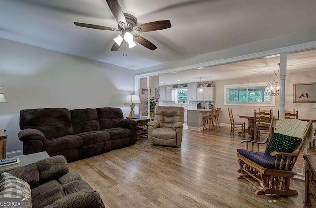 living room featuring wood-type flooring and ceiling fan with notable chandelier