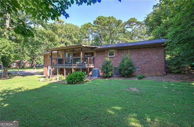 back of property with central AC unit, a deck, and a yard