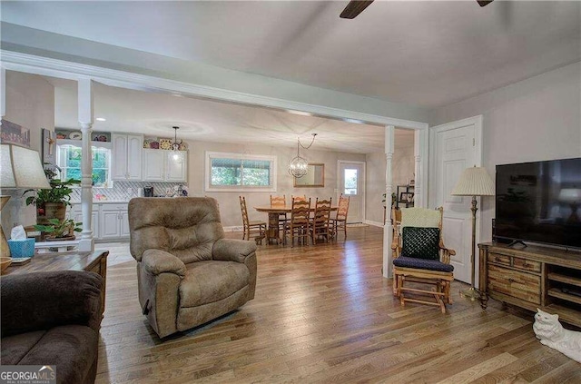 living room with decorative columns, plenty of natural light, and hardwood / wood-style floors