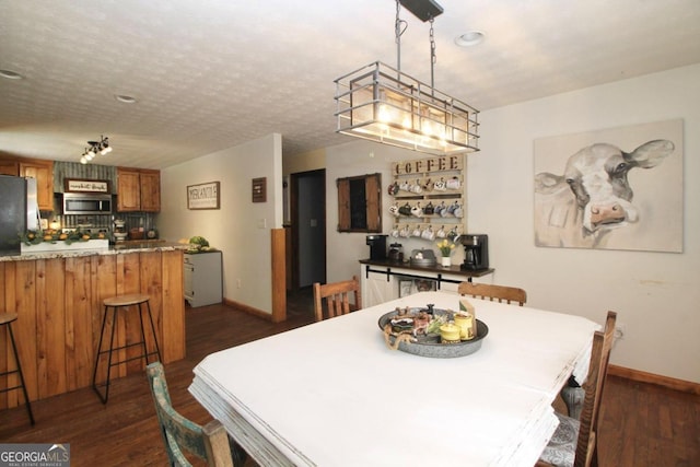 dining space featuring bar and dark wood-type flooring