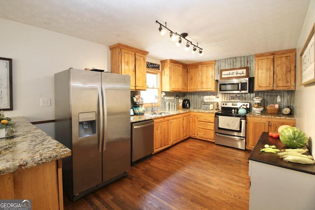 kitchen featuring sink, stainless steel appliances, dark hardwood / wood-style floors, light stone countertops, and decorative backsplash