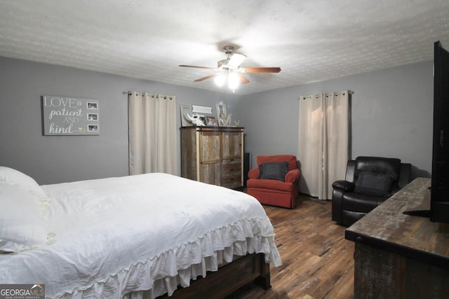 bedroom with ceiling fan, dark hardwood / wood-style floors, and a textured ceiling