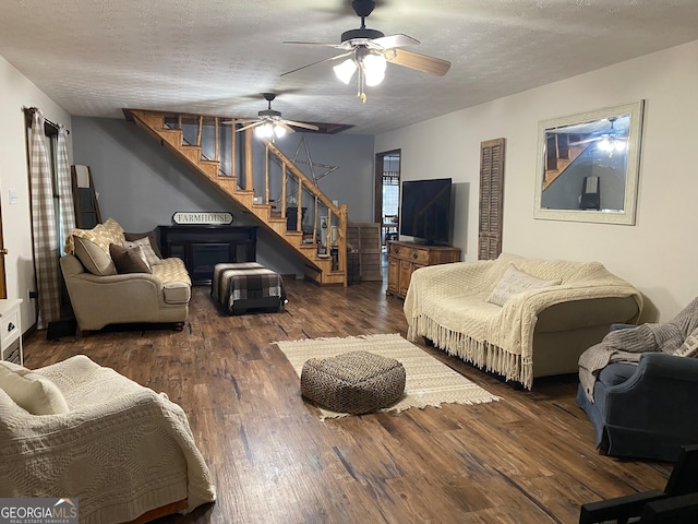 living room featuring ceiling fan, a textured ceiling, and dark hardwood / wood-style floors